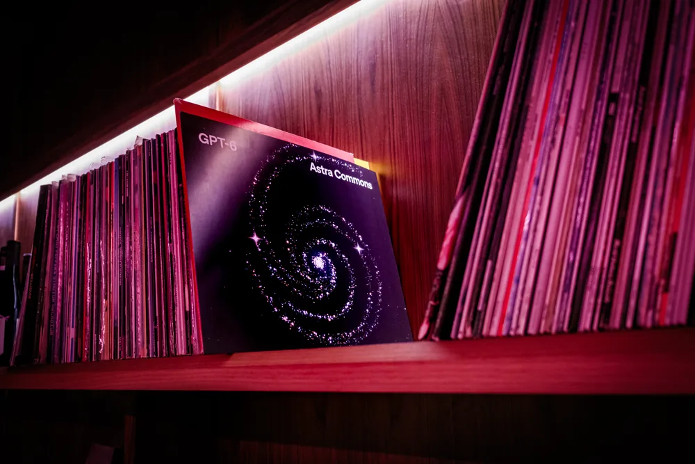 An Astra Commons poster displayed beside vinyl records under red lighting